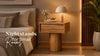 Wooden nightstand for small bedrooms beside a bed in a warm, modern interior.