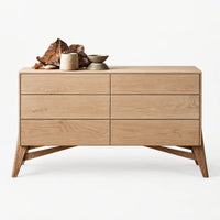 A mid-century modern wooden chest of drawers with six drawers, styled with decorative ceramic vessels and driftwood on top, set against a clean white background.