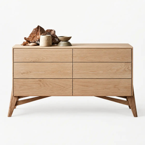 A mid-century modern wooden chest of drawers with six drawers, styled with decorative ceramic vessels and driftwood on top, set against a clean white background.